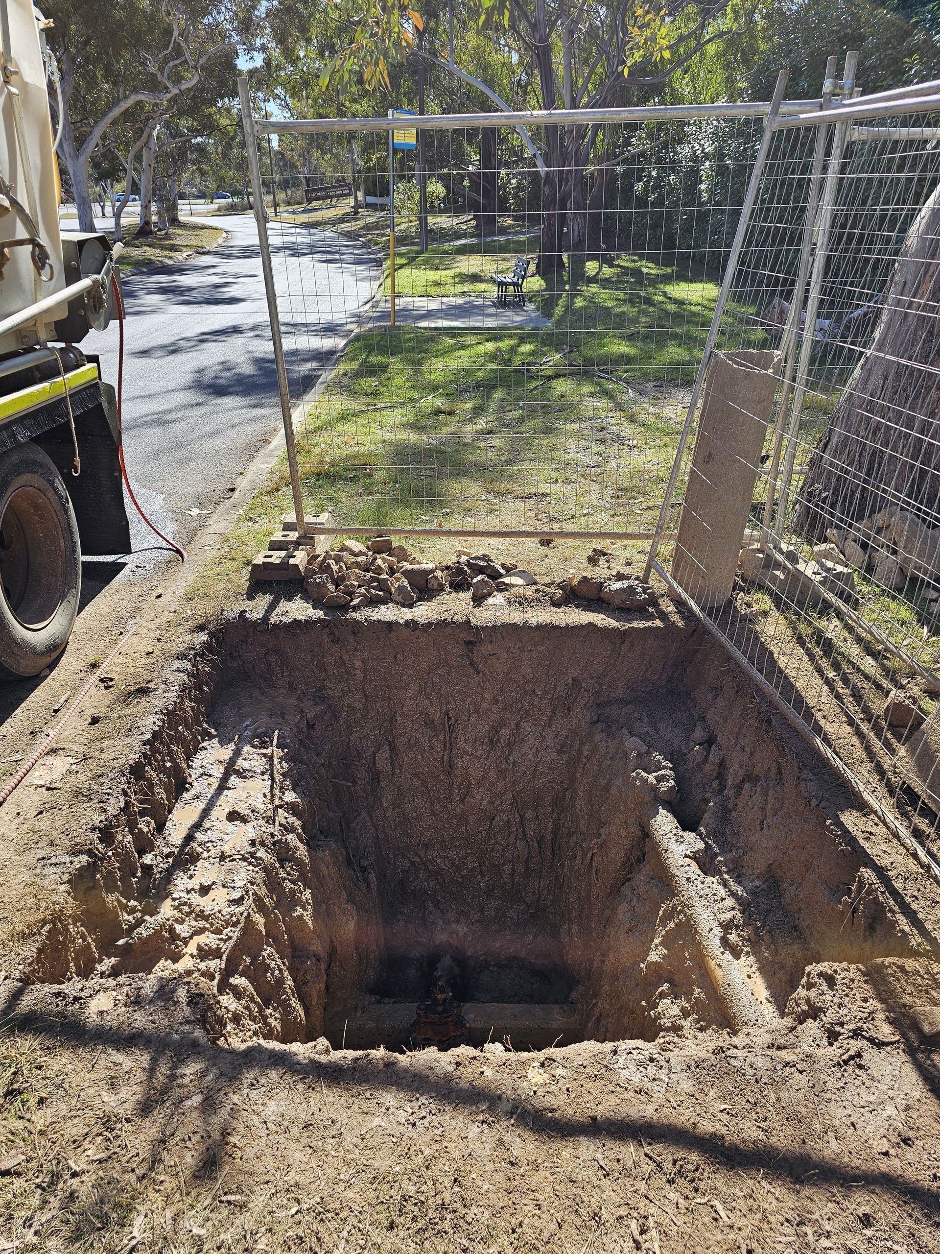 Open square excavation in dirt, with safety fencing around — Pro Pipe Solutions in Queanbeyan, NSW