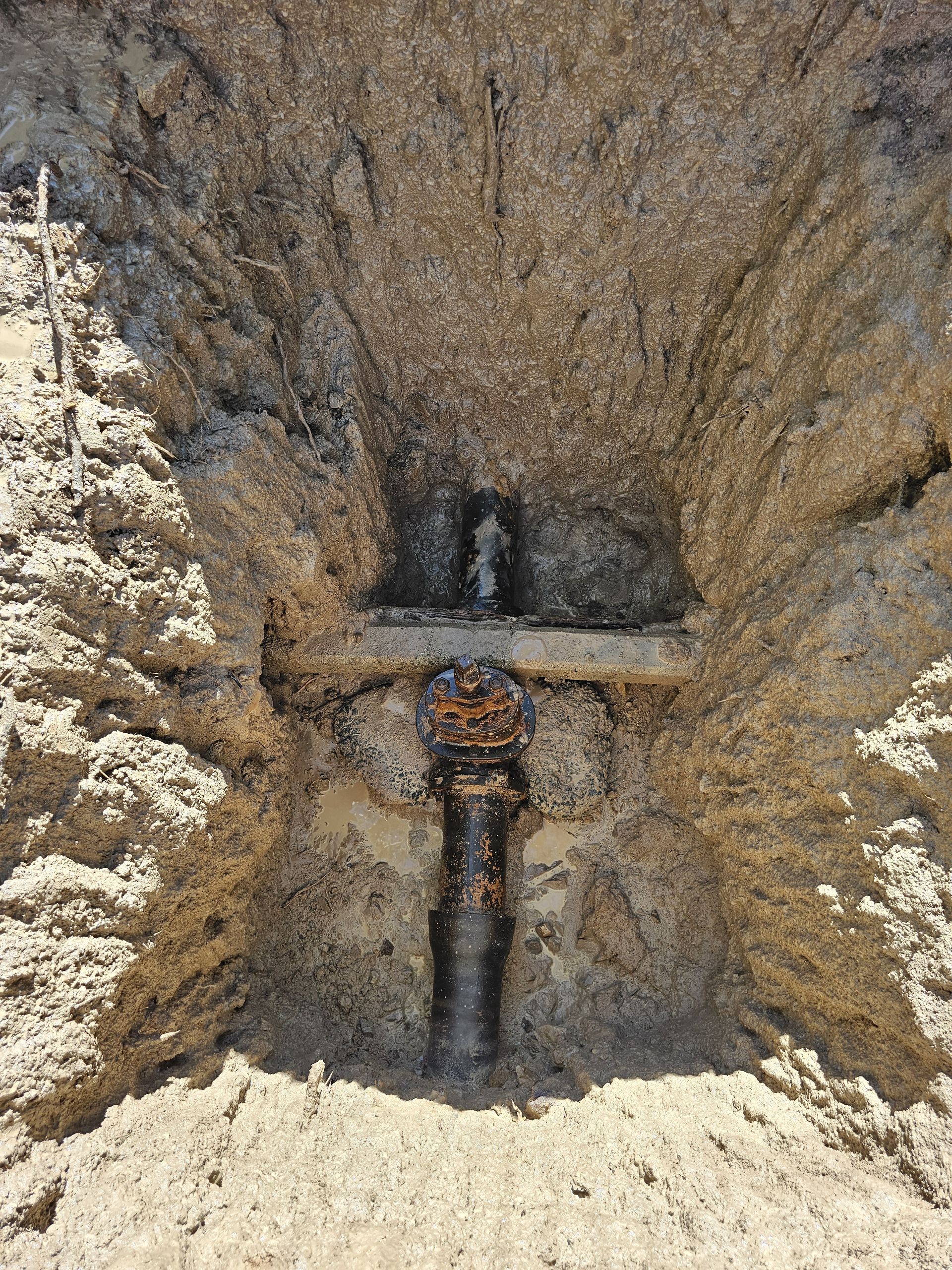 Rust-covered pipe embedded in a sandy, rough-textured wall — Pro Pipe Solutions in Queanbeyan, NSW