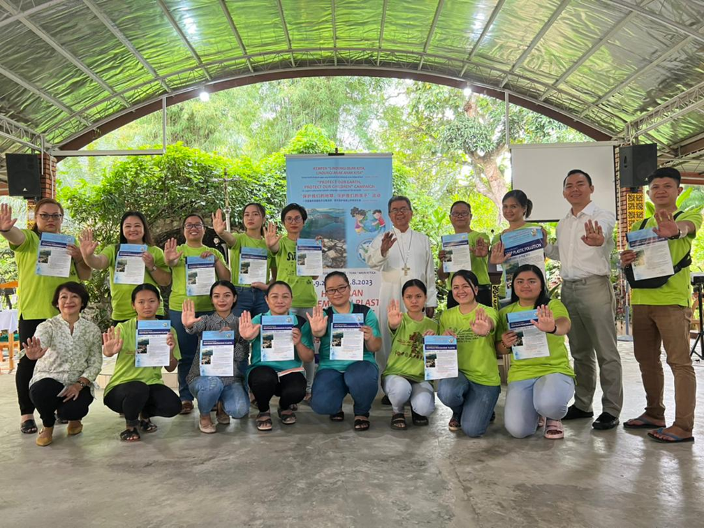 Group of people holding certificates, smiling, posing together outdoors under a canopy.
