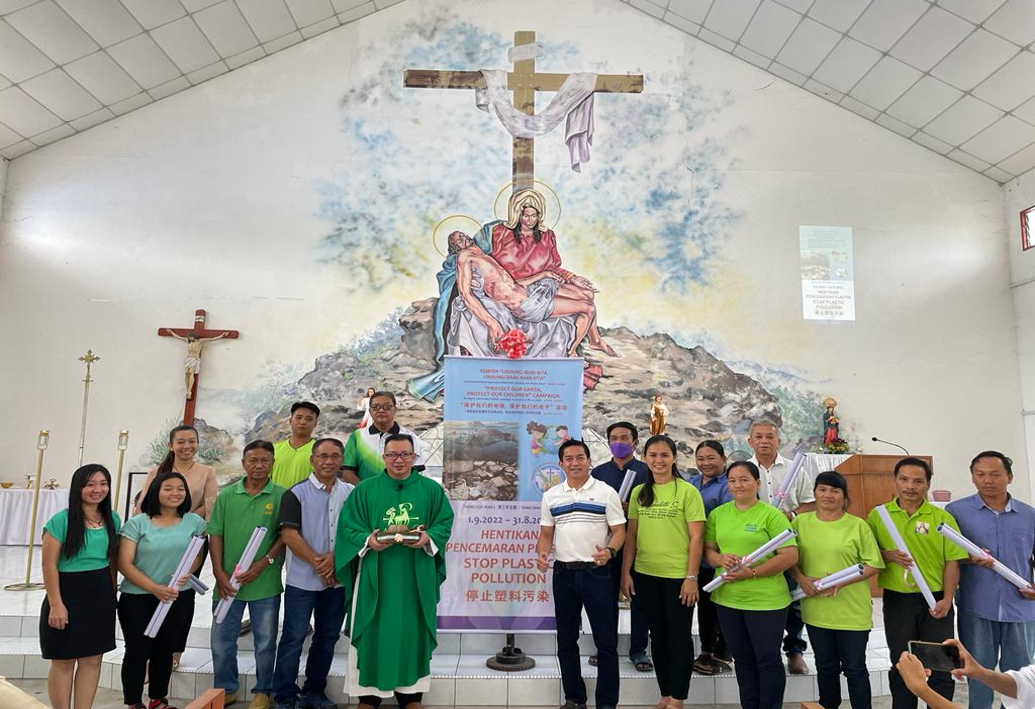 Group of people pose in church before a painted crucifixion scene.
