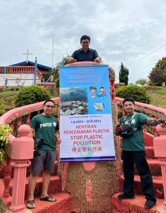 Three people pose with a banner that reads