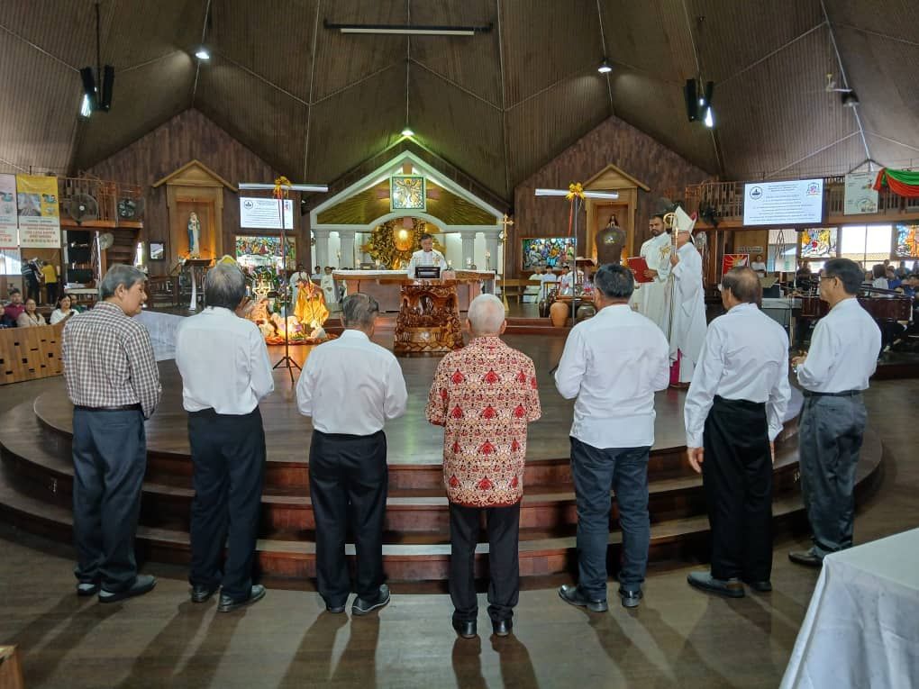 Men in church with altar; priest in white robes.