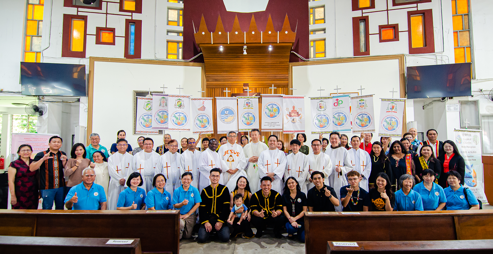 Group of people in a church, smiling at the camera. Banners hang behind them.