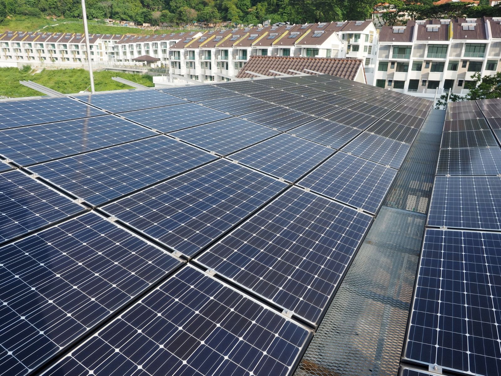 Solar panels installed on a rooftop, with rows of townhouses in the background.
