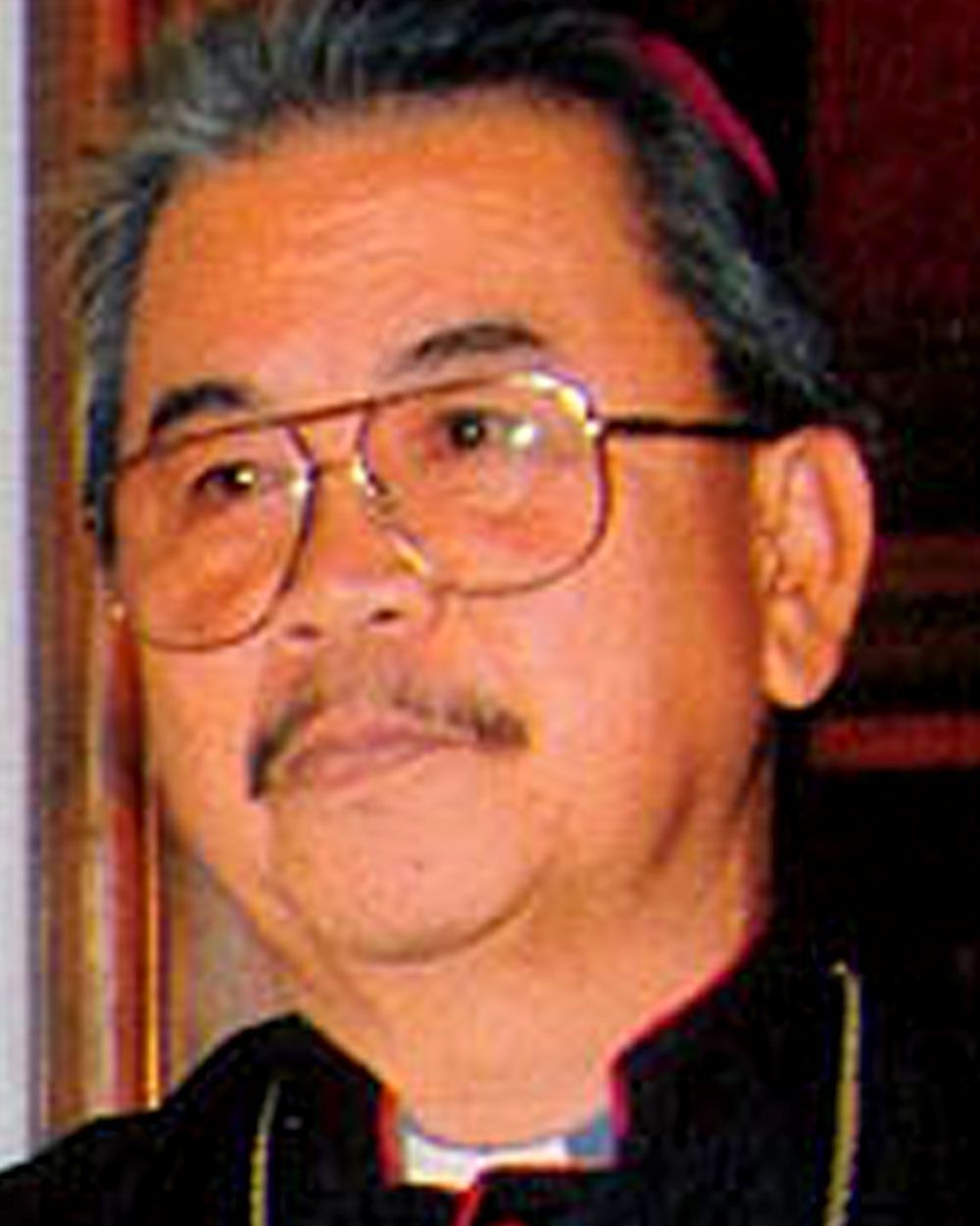 Portrait of a man wearing glasses, mustache, and religious attire.