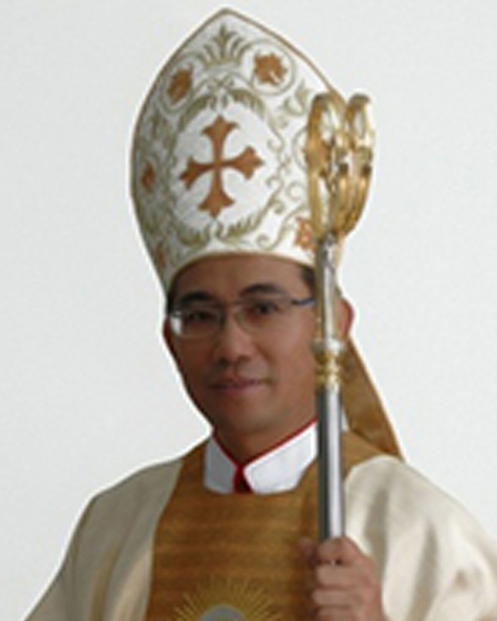 Man in religious vestments, including mitre and pastoral staff, smiling.