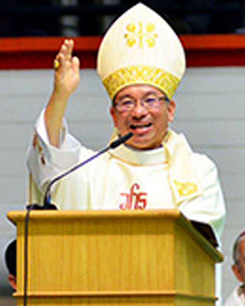 Bishop giving a blessing at a lectern, wearing a mitre and vestments.