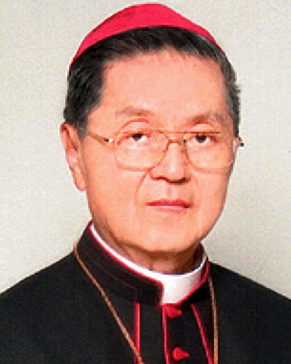 A man wearing a red hat and glasses, in a black robe with a white collar, likely a church leader.
