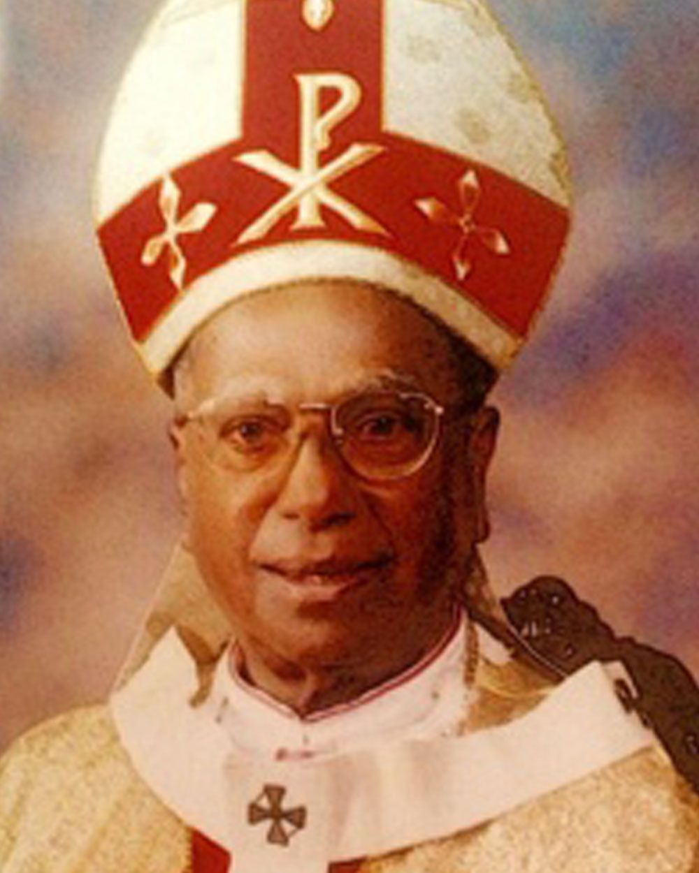 Bishop in white and gold vestments, wearing a mitre with Chi Rho symbol.