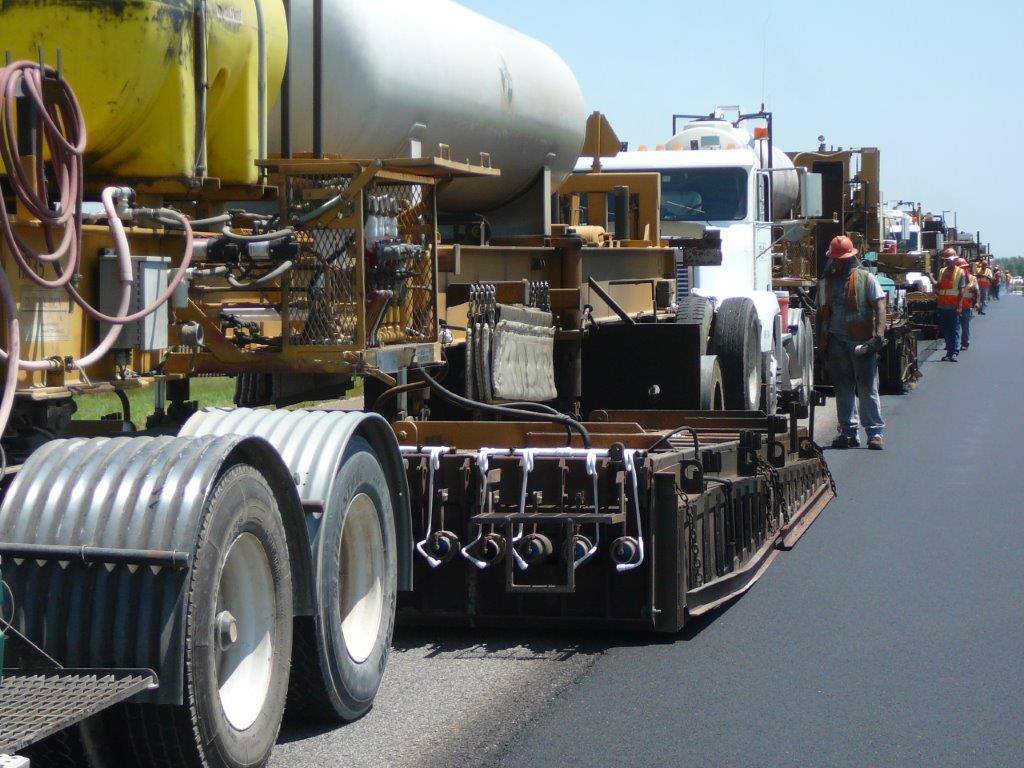 Road paving equipment laying asphalt on a highway.