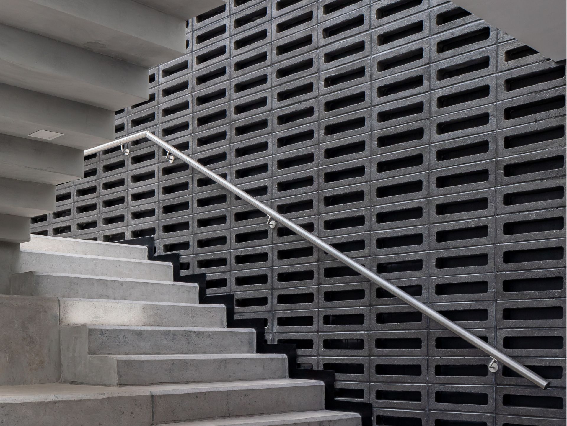 Una escalera con barandilla de metal y una pared de ladrillo detrás.