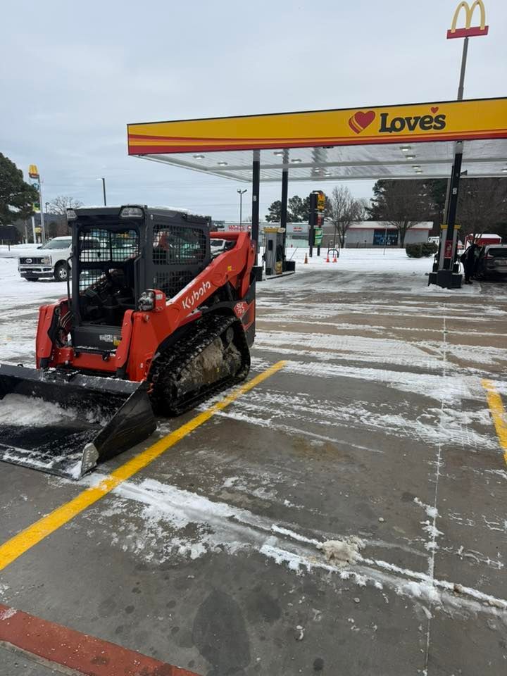 An orange Kubota skid-steer loader parked in a snowy Love’s gas station parking lot.