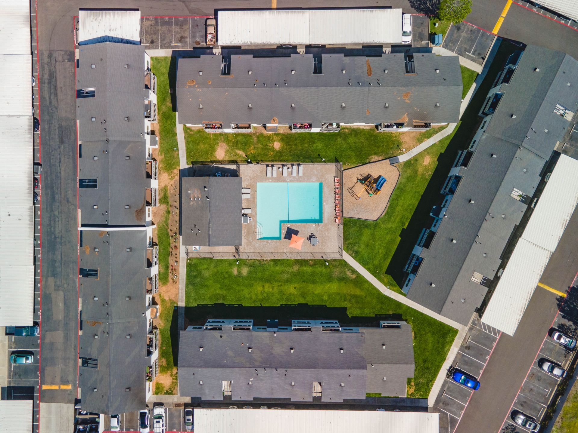 Aerial view of apartment buildings around a central courtyard with a blue swimming pool.