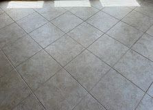 Gray tiled floor with diagonal grout lines and bright light reflections near the top edge