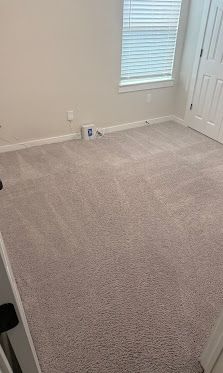 Empty beige carpeted room with white walls, a window, and a closet door.