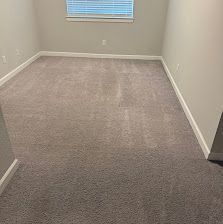 Empty beige carpeted room with white walls and a window with blinds