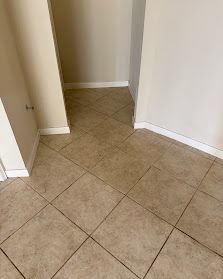 Narrow tiled hallway corner with beige walls and white baseboards