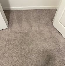 Carpeted hallway corner with open white doors and a baseboard along the wall