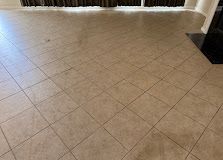 Beige tiled floor in a room with a white wall and dark curtain or doorway edge