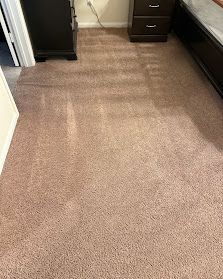 Narrow carpeted hallway or closet floor with beige-brown carpet and dark furniture along the sides