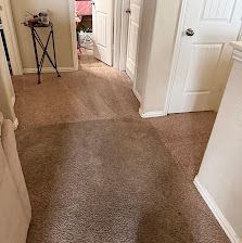Carpeted hallway with open white doors and a small table in the corner