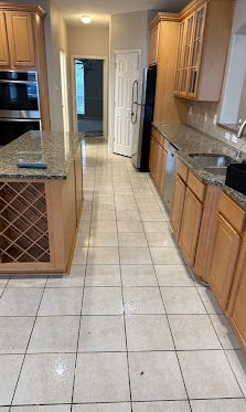 Kitchen with beige tile floor, granite counters, wooden cabinets, and stainless steel appliances.