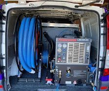 Open van interior with blue hoses and carpet cleaning equipment mounted inside.
