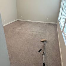 Vacuum on a beige carpet in an empty room near a window.