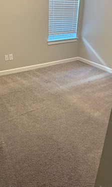 Empty beige carpeted room with gray walls and a small window with blinds
