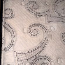 Close-up of a white mattress with gray quilted swirls and tufted buttons