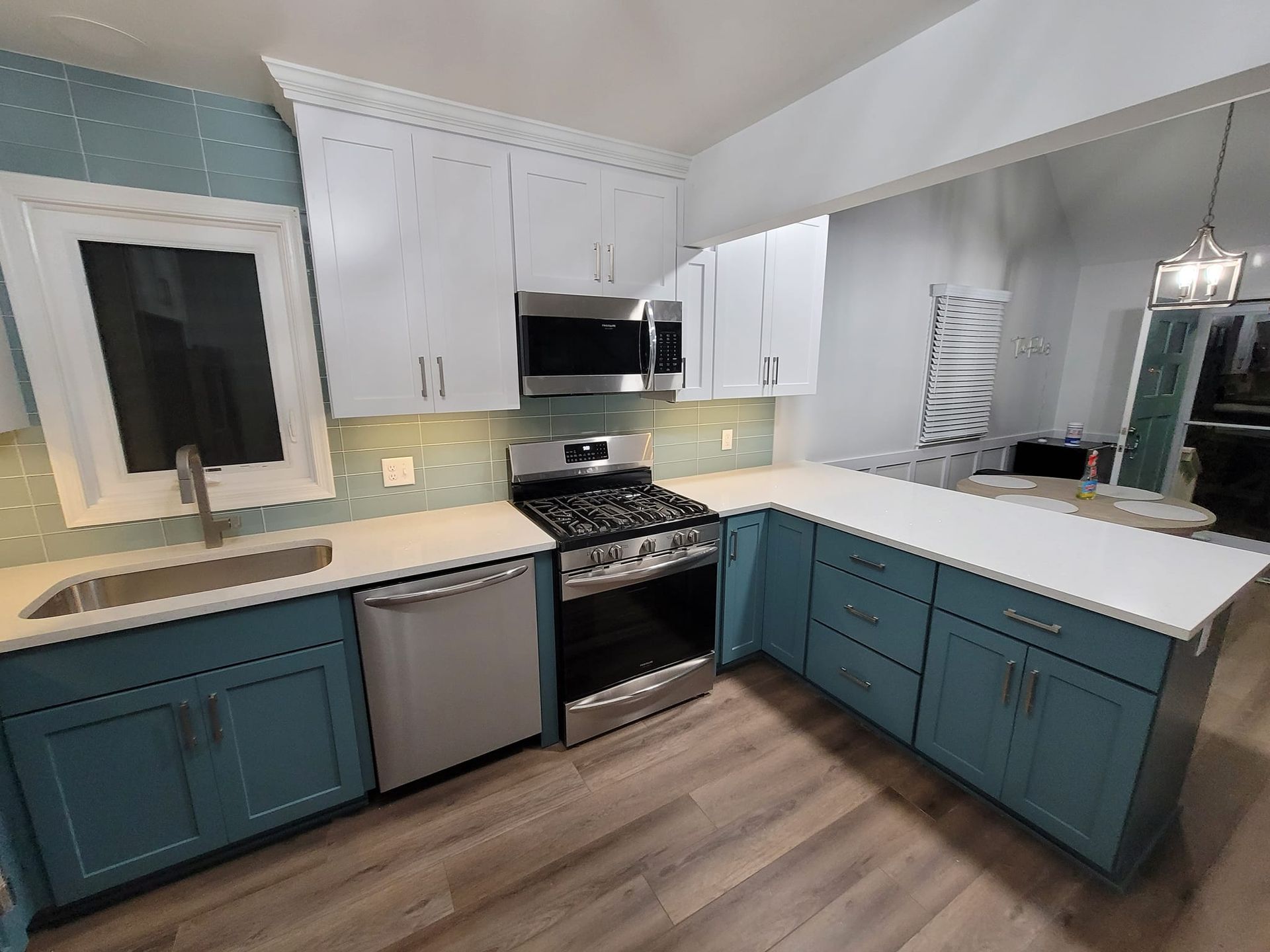 A kitchen with blue cabinets, white counter tops, stainless steel appliances and a stove.