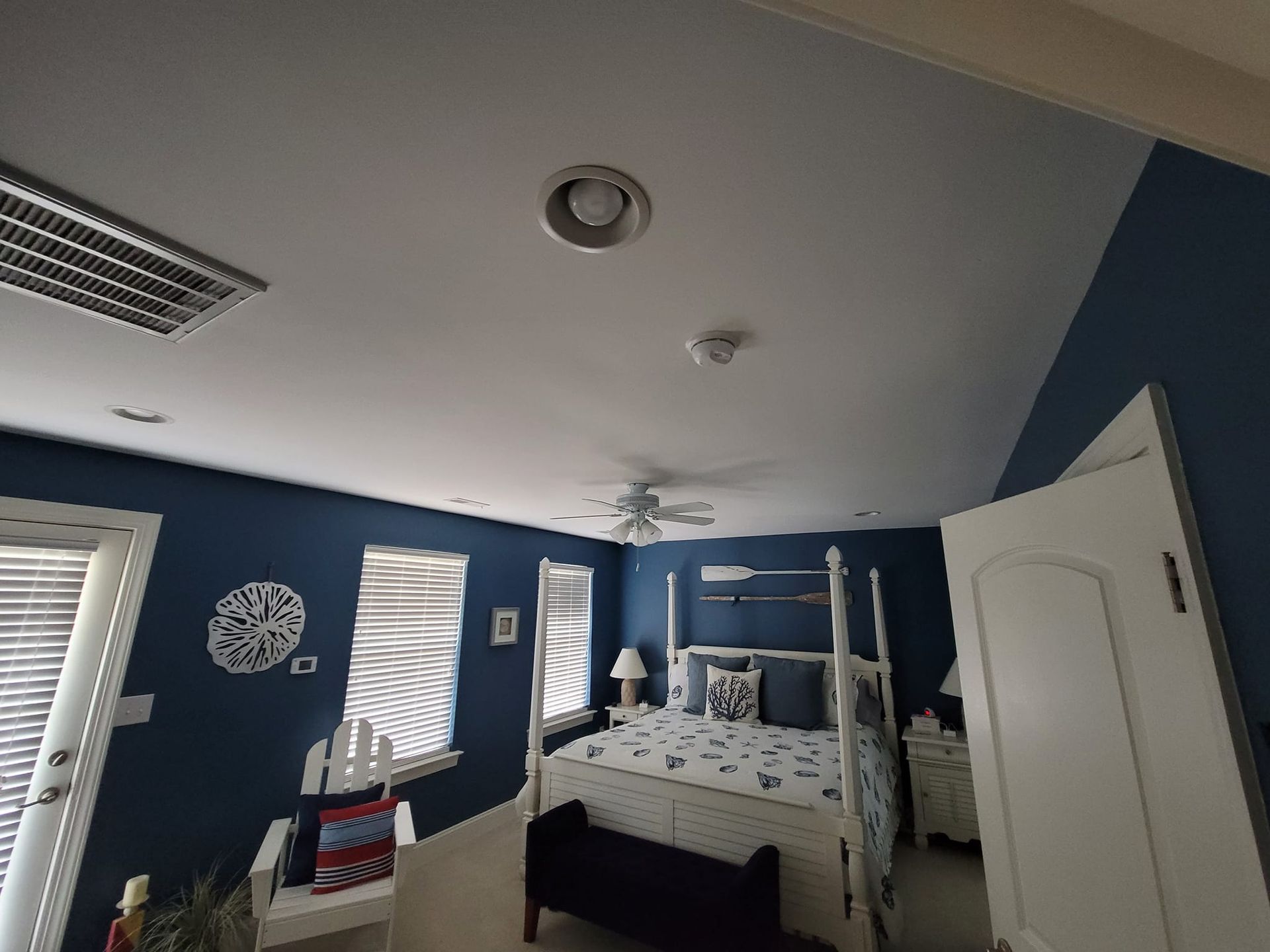 A bedroom with a four poster bed and a ceiling fan.