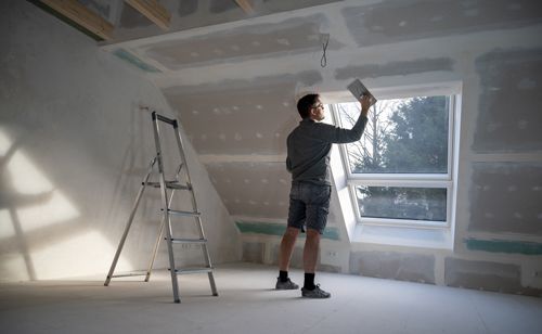 A man is standing in an empty room in front of a window.