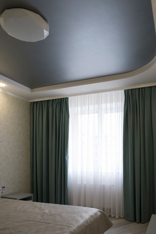 A bedroom with a bed, curtains and a ceiling light.