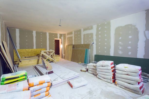 A room under construction with a lot of bags of cement on the floor.