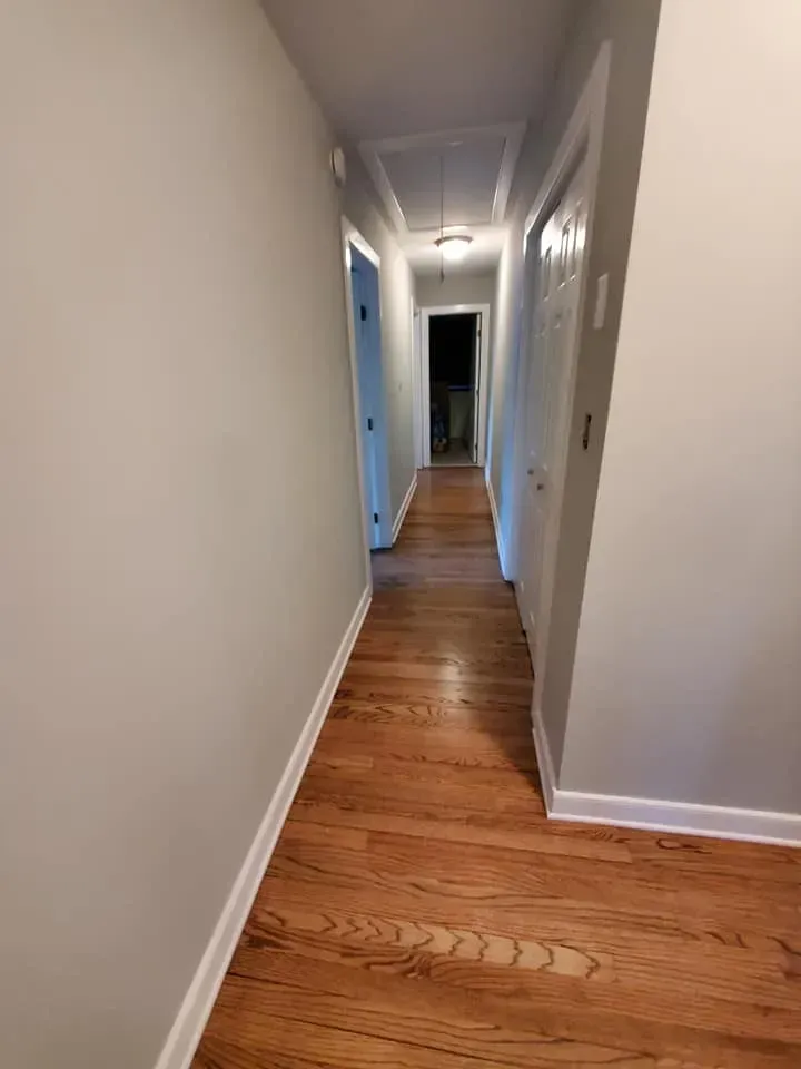 A long hallway with hardwood floors and white walls.