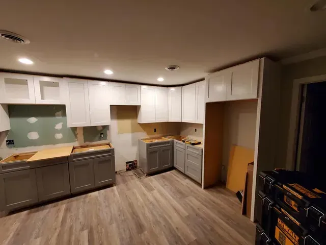 A kitchen with white cabinets and wooden floors is being remodeled.