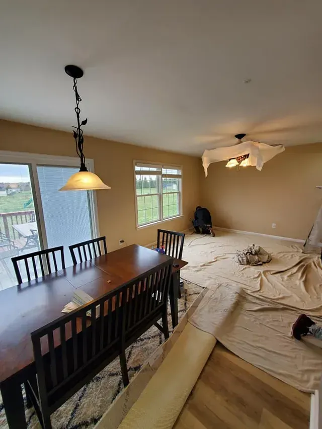 A living room with a table and chairs and a ceiling fan.