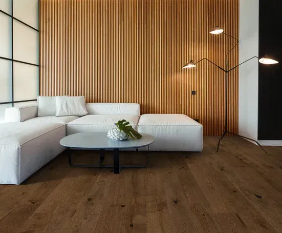A living room with a couch , table , lamp and wooden wall.