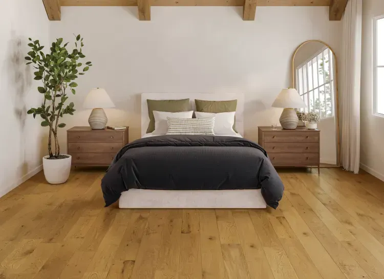 A bedroom with hardwood floors , a bed , dresser , and mirror.