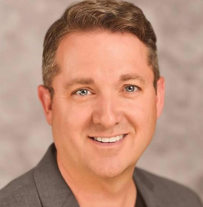 A man in a suit is smiling for the camera.