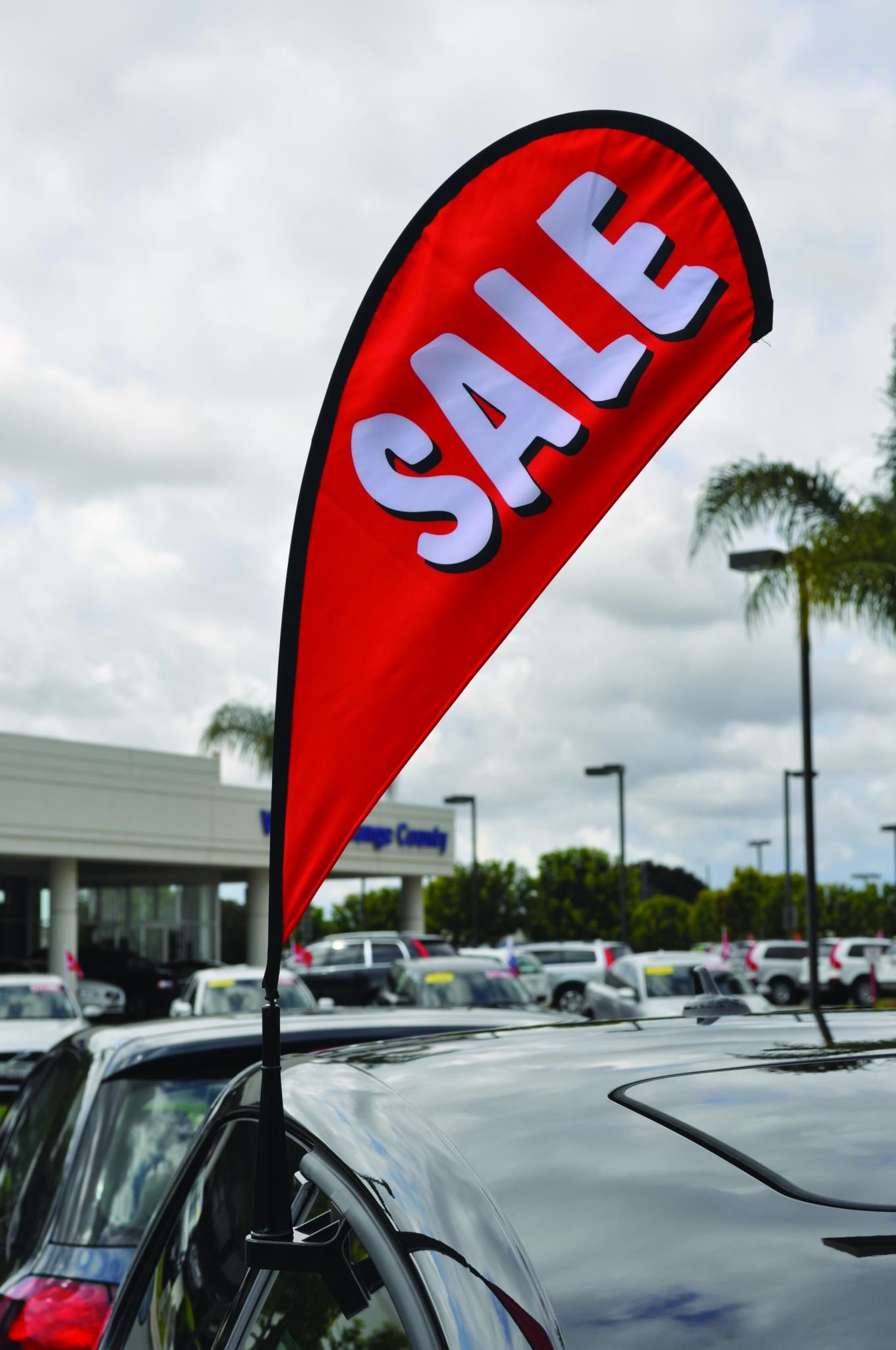 A red sale flag is hanging from the windshield of a car