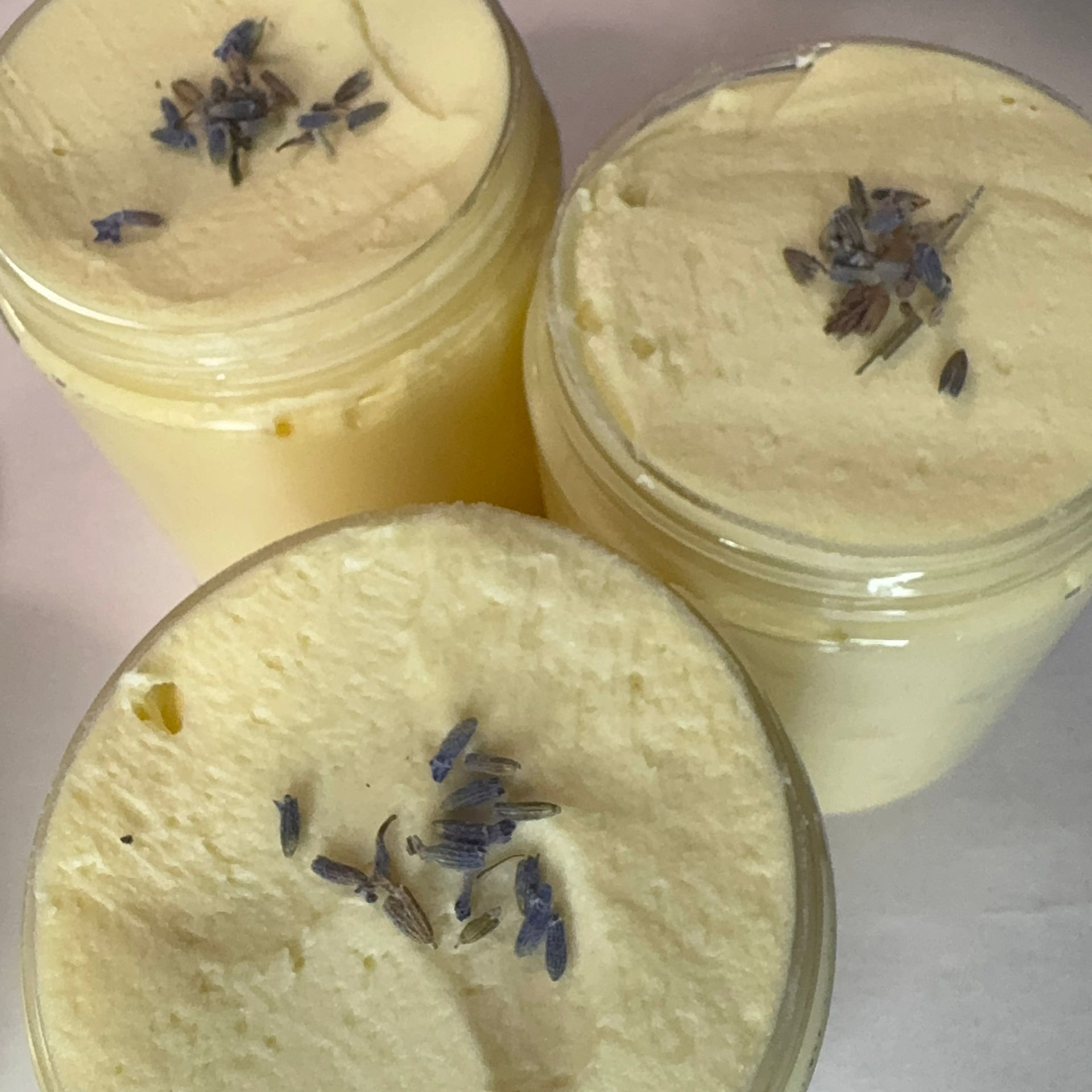 Three clear jars of body butter with lavender sprigs.