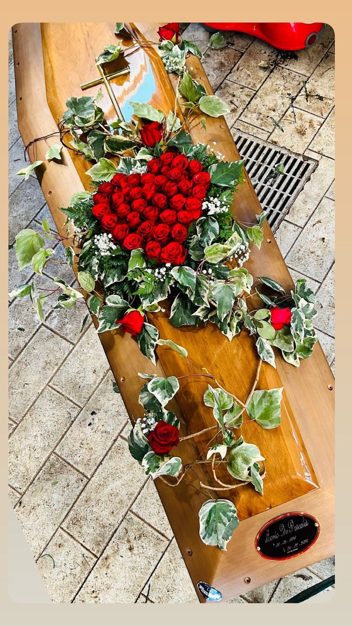 Una tavola di legno decorata con una composizione a forma di cuore rosso, edera e rose rosse.
