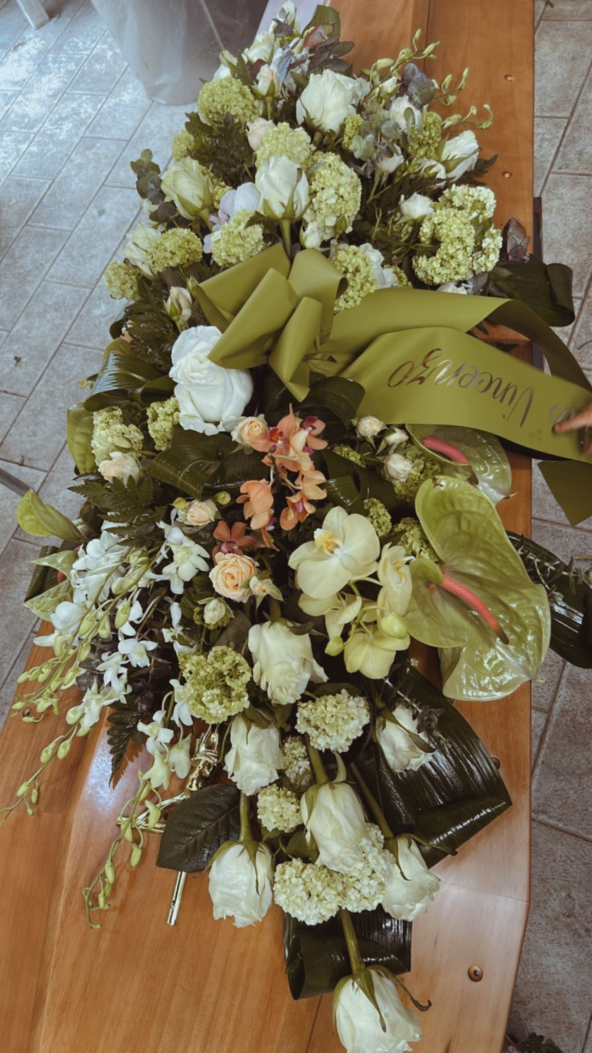 Composizione floreale su una superficie di legno, con fiori bianchi e verdi, con un fiocco verde e verde.