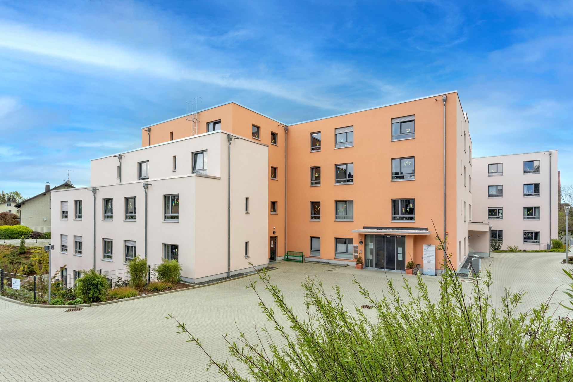 Moderne Häuser der Altenpflege des gesundheitscampus Quirlsberg mit Sträuchern und einem sonnigen Himmel.