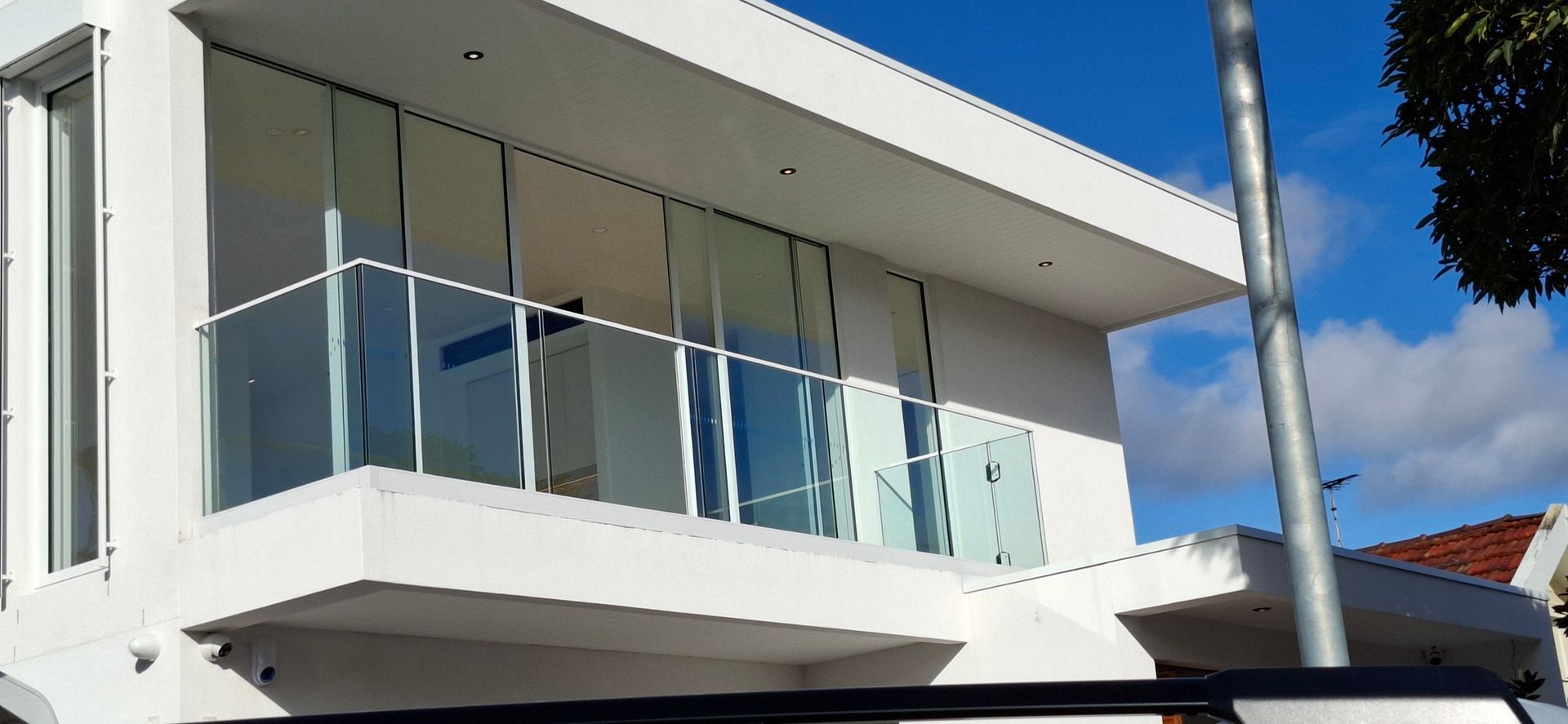 White modern house with glass balcony, blue sky - Sydney, NSW - Alta Trading Pty Ltd White modern house with glass balcony, blue sky - Sydney, NSW - Alta Trading Pty Ltd