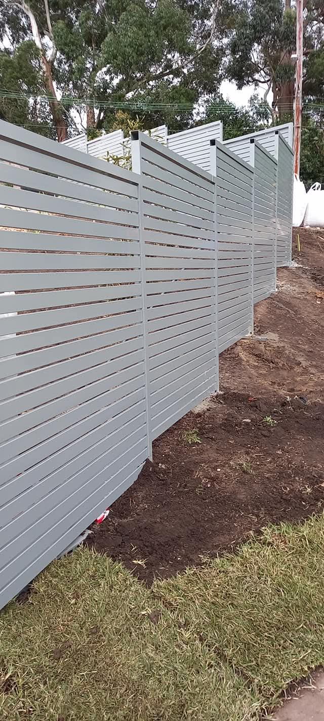 A long, gray horizontal slat fence along a grassy hill - Sydney, NSW - Alta Trading Pty Ltd A long, gray horizontal slat fence along a grassy hill - Sydney, NSW - Alta Trading Pty Ltd