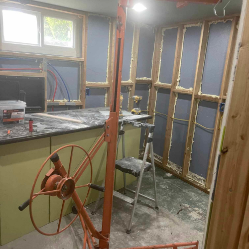 Interior construction, drywall lift near partially framed walls, insulation visible, small ladder.