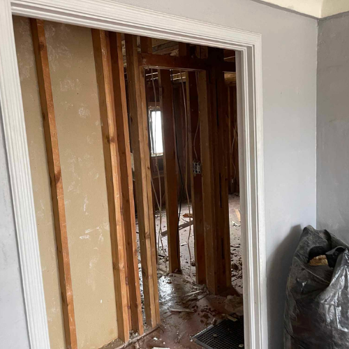 A doorway opening into a room under renovation, exposing studs and debris.